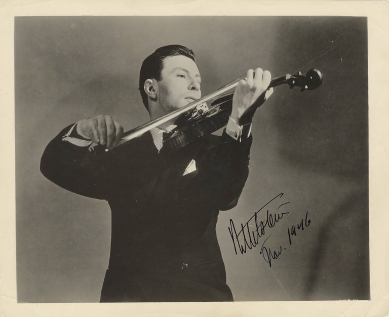 Item #39133 Half-length glossy publicity photograph of the noted violinist bowing his instrument. Nathan MILSTEIN.